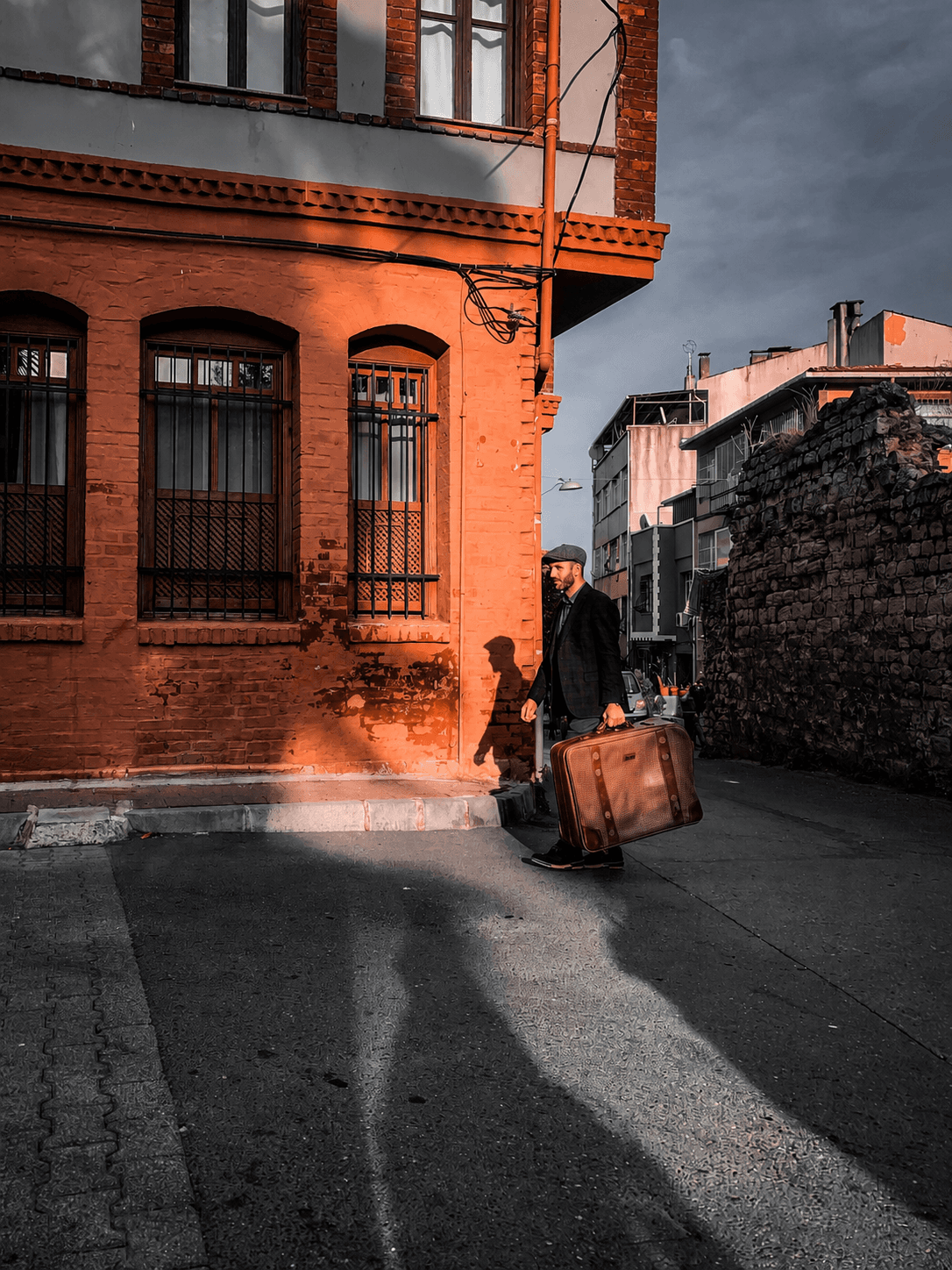 Valiziyle kent içinde yürüyen bir kişi, göç ve sosyal uyum temasını simgeliyor